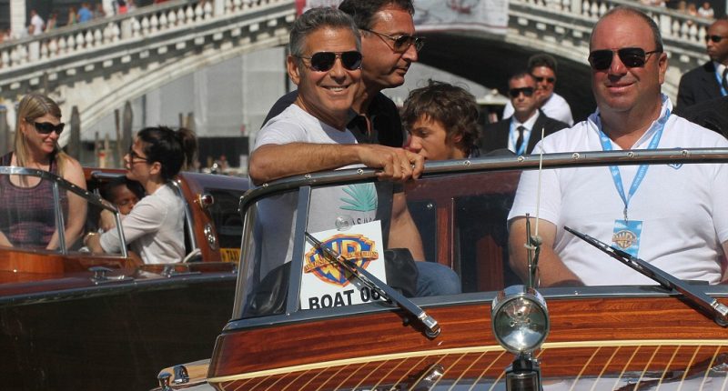 George Clooney, old friend Sandra Bullock and her son Louis cruise through Venice's canals ahead of film festival