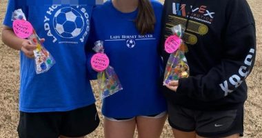 Three girls holding birthday treats, one wearing a Lady Hornet Soccer sweatshirt.