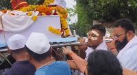 A man carrying his brother's coffin at a funeral procession.