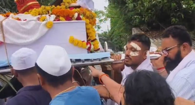 A man carrying his brother's coffin at a funeral procession.