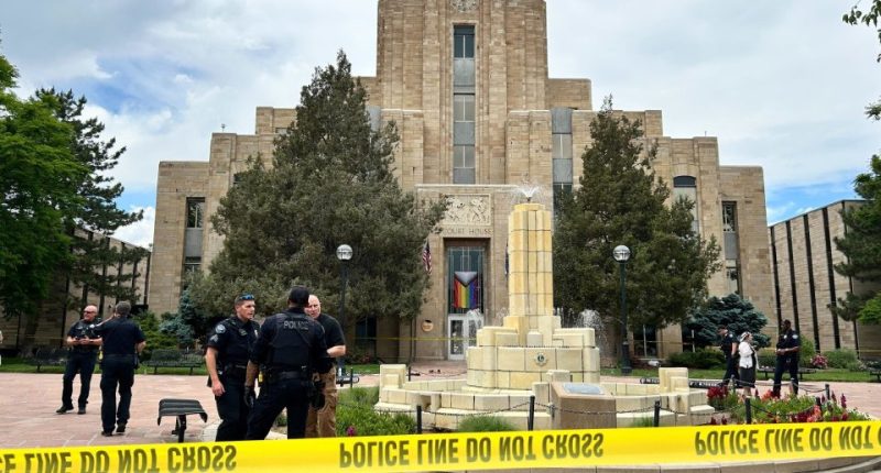 Police officers investigating a scene in front of a courthouse.