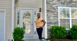 A woman stands in front of her house, which has a new fence that was allegedly installed by her HOA without permission.