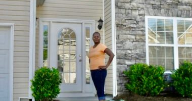A woman stands in front of her house, which has a new fence that was allegedly installed by her HOA without permission.