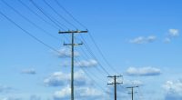 Power lines against a blue sky with fluffy clouds.