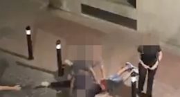 A man being restrained on the ground by another man.