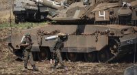 An Israeli soldier carries a shell next to a tank in northern Israel on Friday, September 27.
