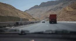 cars drive on highway through arid mountains