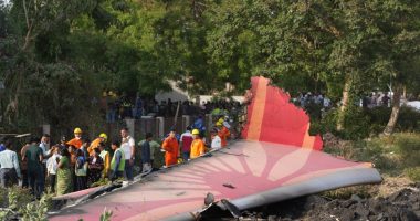 Debris of a crashed airplane with people standing nearby.