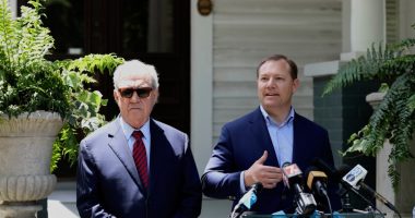 Two men in suits speak at a press conference.