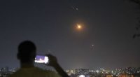 A man takes a cellphone photo as missiles fired from Iran toward Israel fly over Syrian territory in Damascus, Syria, early Wednesday, June 18, 2025. (AP Photo/Ghaith Alsayed)