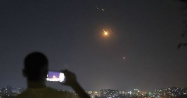 A man takes a cellphone photo as missiles fired from Iran toward Israel fly over Syrian territory in Damascus, Syria, early Wednesday, June 18, 2025. (AP Photo/Ghaith Alsayed)
