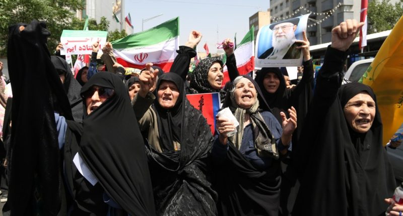 Thousands of Iranians waving flags and protesting.