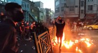 Protestors at night burning debris in a city street.