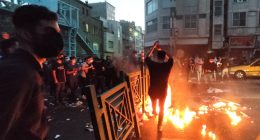 Protestors at night burning debris in a city street.