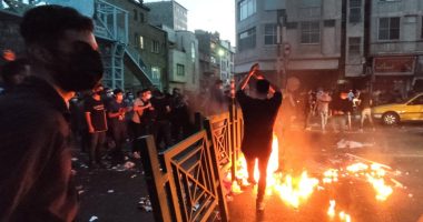 Protestors at night burning debris in a city street.