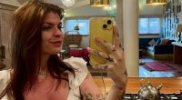 Selfie of a woman with tattoos taking a selfie in a kitchen.