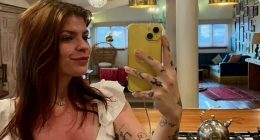 Selfie of a woman with tattoos taking a selfie in a kitchen.
