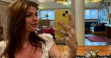 Selfie of a woman with tattoos taking a selfie in a kitchen.