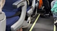 Airplane aisle with passengers seated.