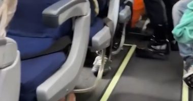 Airplane aisle with passengers seated.
