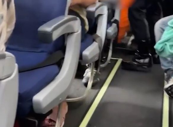 Airplane aisle with passengers seated.