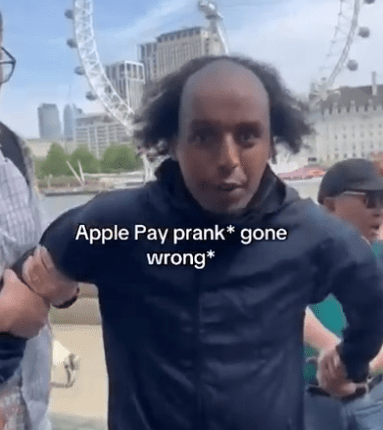 Man being detained, Apple Pay prank gone wrong, London Eye in background.