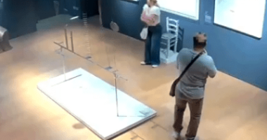 High-angle view of two people in an art gallery near a damaged art installation.