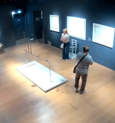 High-angle view of two people in an art gallery near a damaged art installation.