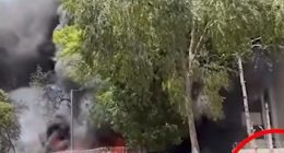 Large fire with people watching from a distance.