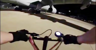 First-person view of a person riding a bike at night near airplanes.