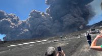 Mount Etna erupting, with people taking photos.