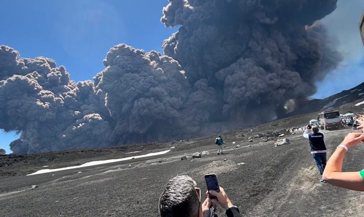 Mount Etna erupting, with people taking photos.