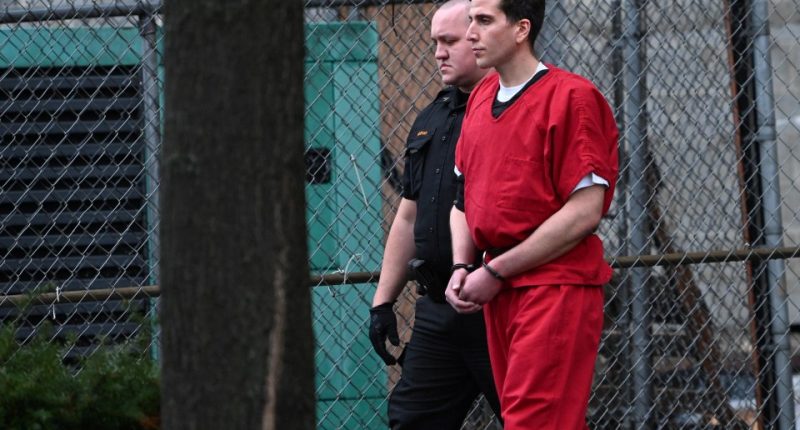 Bryan Kohberger in handcuffs, wearing a red jumpsuit, escorted by a law enforcement officer.