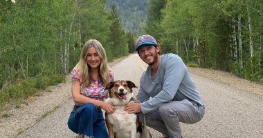 Couple and dog posing on a road in a mountainous area.