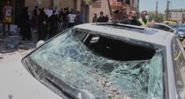 People gather next to a car that was damaged in an Israeli airstrike in Nabatieh town, south Lebanon, Friday, June 27, 2025. (AP Photo/Mohammed Zaatari)