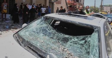 People gather next to a car that was damaged in an Israeli airstrike in Nabatieh town, south Lebanon, Friday, June 27, 2025. (AP Photo/Mohammed Zaatari)