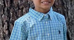 Photo of a young boy in a blue and green checkered shirt.