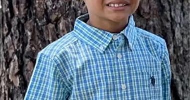 Photo of a young boy in a blue and green checkered shirt.
