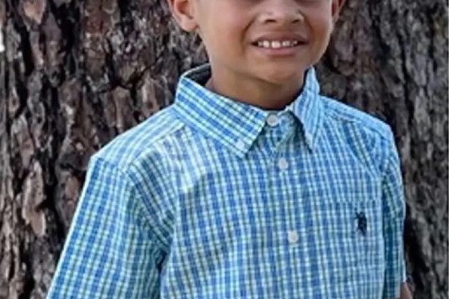 Photo of a young boy in a blue and green checkered shirt.