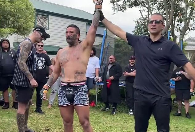 Pictured: UFC star Dan Hooker (left, in baseball cap and singlet) watches as gang member Jon Paul 'Fightdog' Te Rito is awarded a win in his backyard fight fest in Auckland