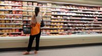 Woman shopping for sausages in a grocery store.