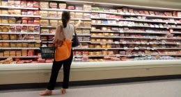 Woman shopping for sausages in a grocery store.