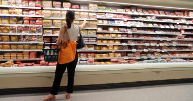 Woman shopping for sausages in a grocery store.