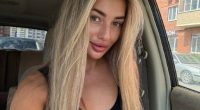 Photo of a young woman with long blonde hair sitting in a car.