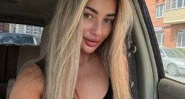 Photo of a young woman with long blonde hair sitting in a car.