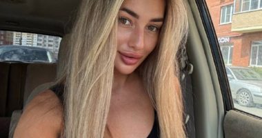 Photo of a young woman with long blonde hair sitting in a car.