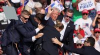 U.S. President Donald Trump gestures with a bloodied face while he is assisted by U.S. Secret Service personnel after he was shot