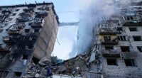 Rescue worker searching for survivors in rubble of bombed building.