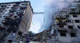 Rescue worker searching for survivors in rubble of bombed building.