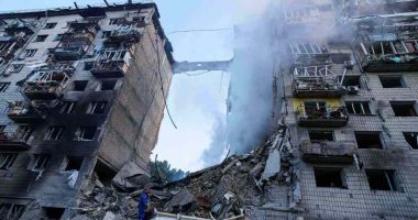 Rescue worker searching for survivors in rubble of bombed building.